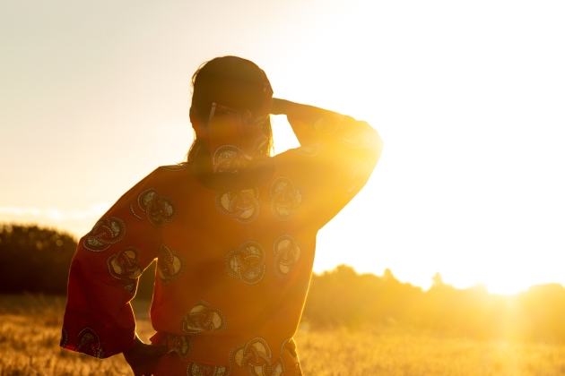 Woman dressed in African traditional clothing looking into the sunset